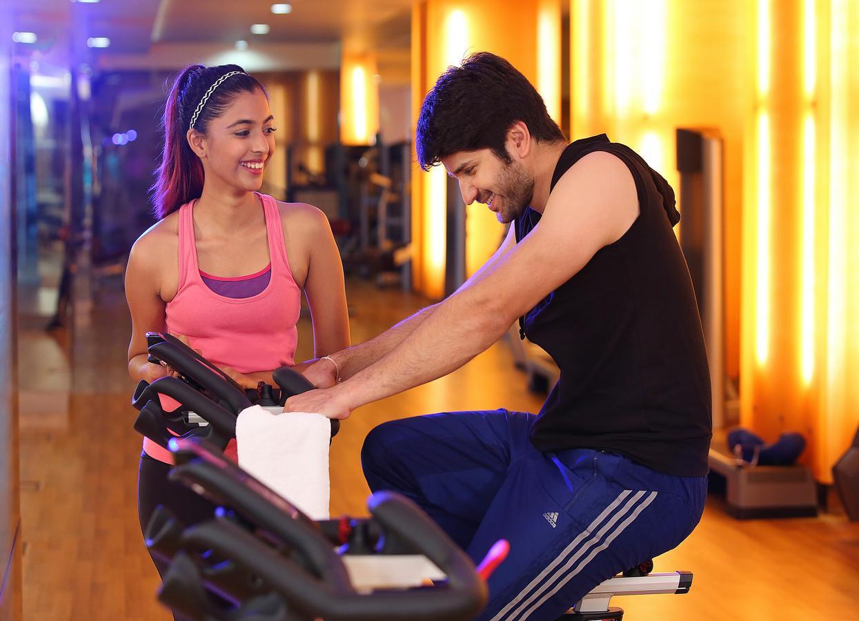 Novotel Hyderabad Airport Exteriör bild A personal trainer assisting a woman on a stationary bicycle